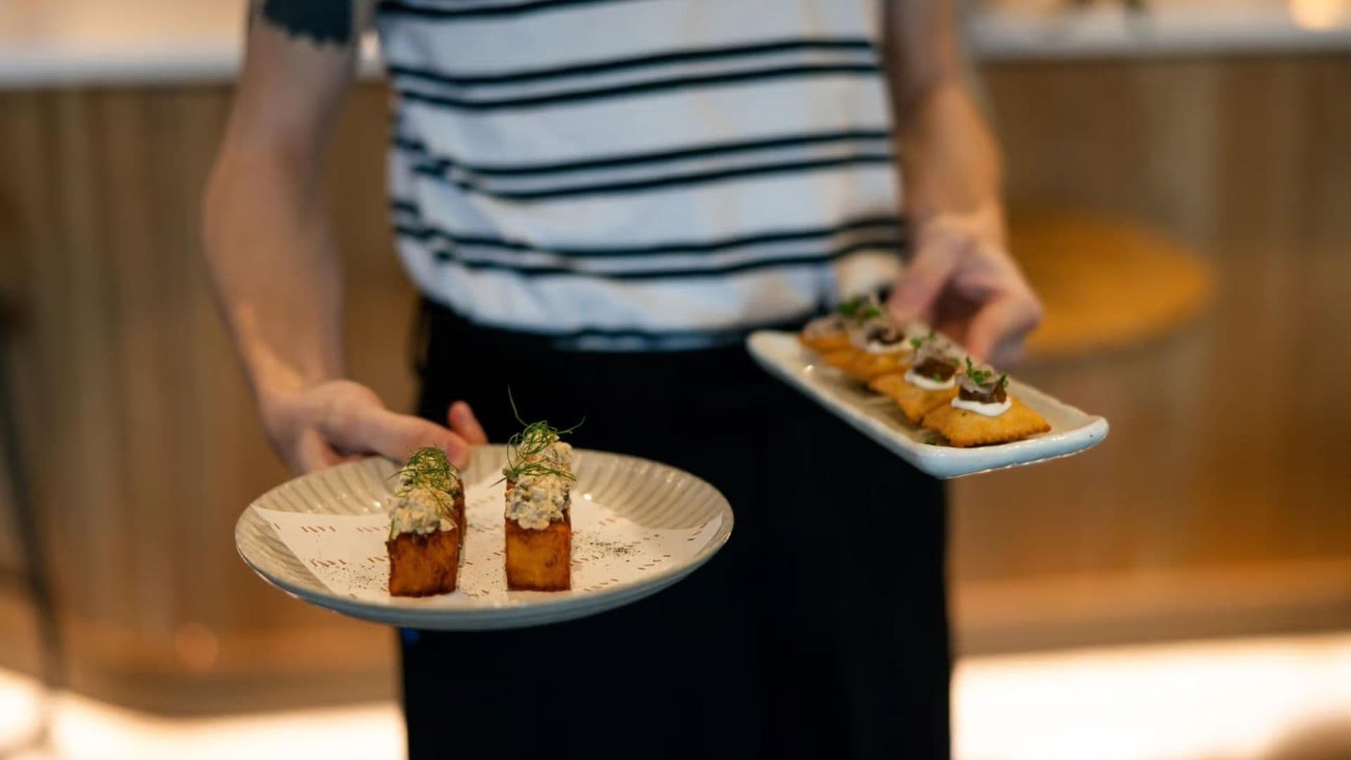 A server carrying plated share dishes to a table at Earl